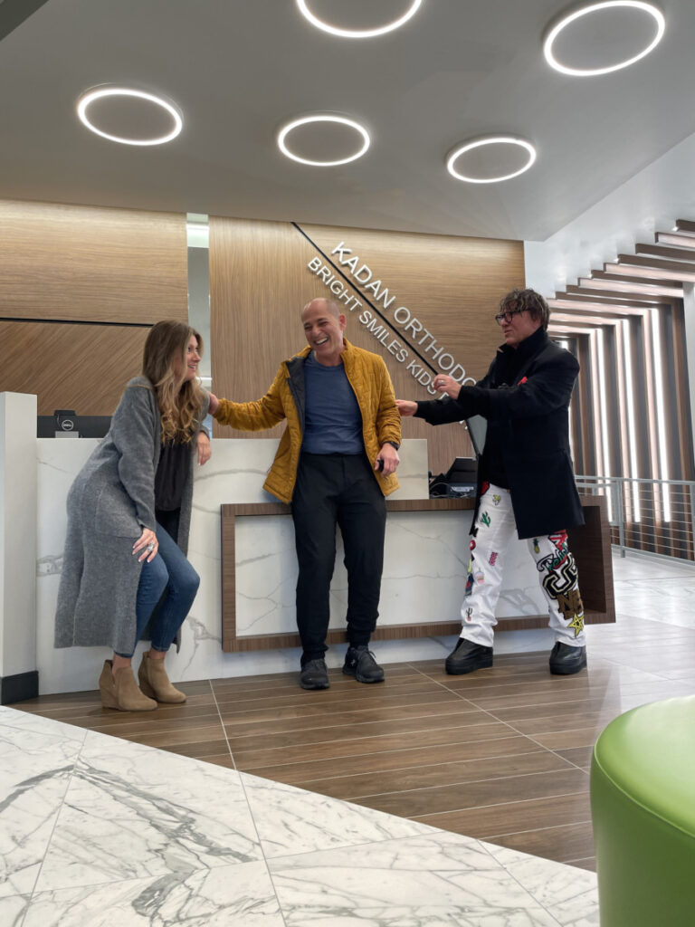 Orthodontic office lobby with angular wood trellises, sculptural geometry, and layered lighting — Kadan Orthodontics, Devon PA by Green Curve Studio.