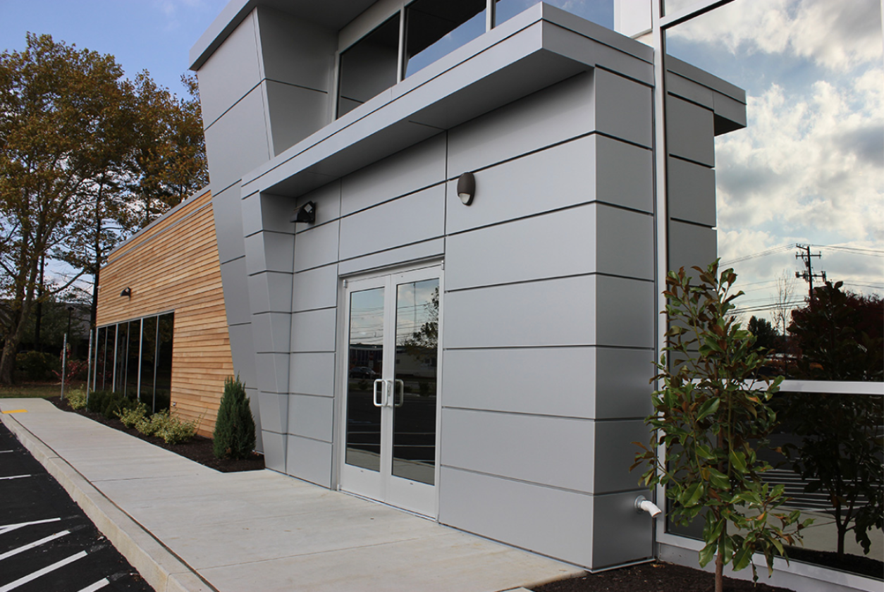 Modern dental office entrance with angled aluminum panels, wood siding, and glass windows — Sparks Orthodontics Bethlehem PA