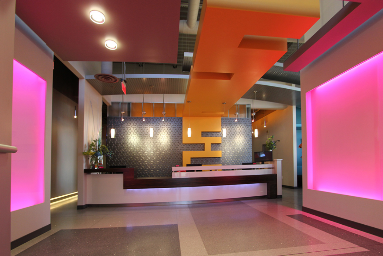 Modern orthodontic reception area with geometric ceiling design, pink accent lighting, and custom logo wall — Sparks Orthodontics Bethlehem PA